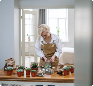 A woman taking care of small pots of interior green plants